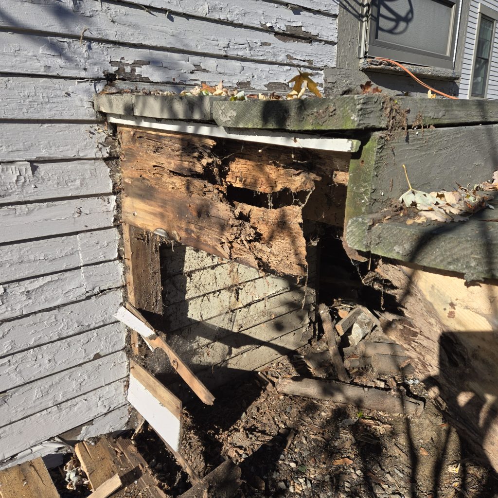 Severely rotted wooden deck stairs and crumbling frame, showing the need for structural repair and replacement.
