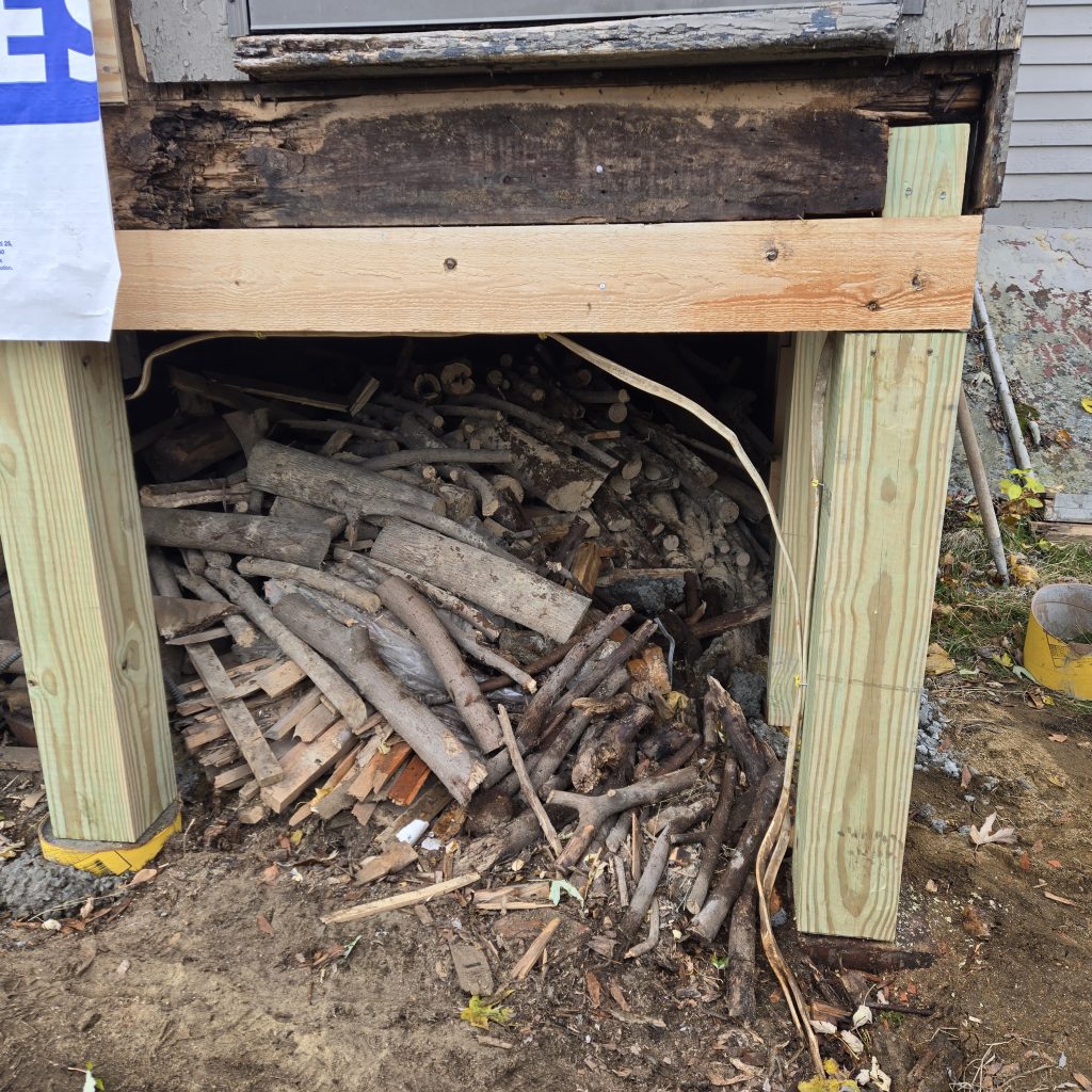 New pressure-treated support posts and beam installed to replace rotted structural framing underneath an exterior addition.