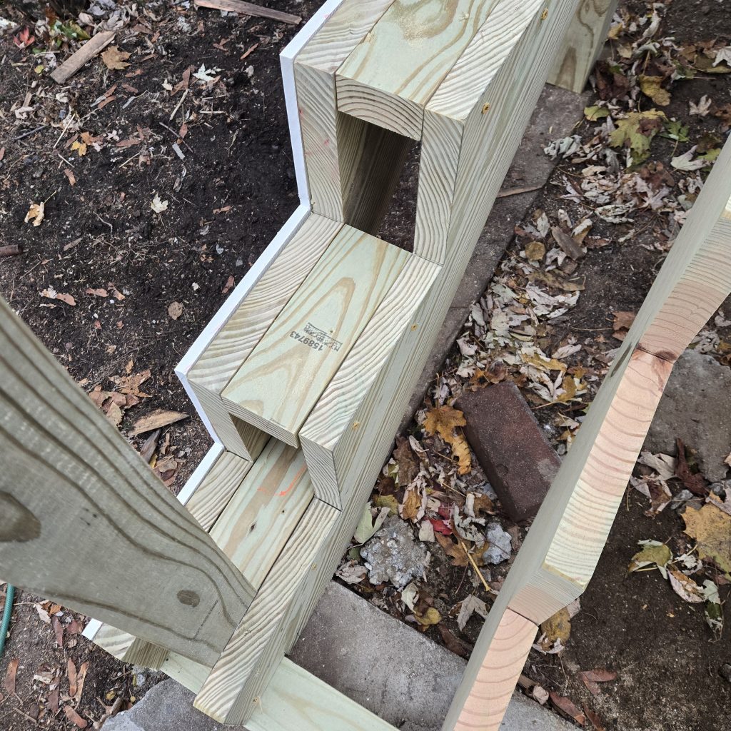 Overhead close-up view of heavy-duty pressure-treated stair stringers and solid blocking, demonstrating robust construction techniques for a new deck entrance.