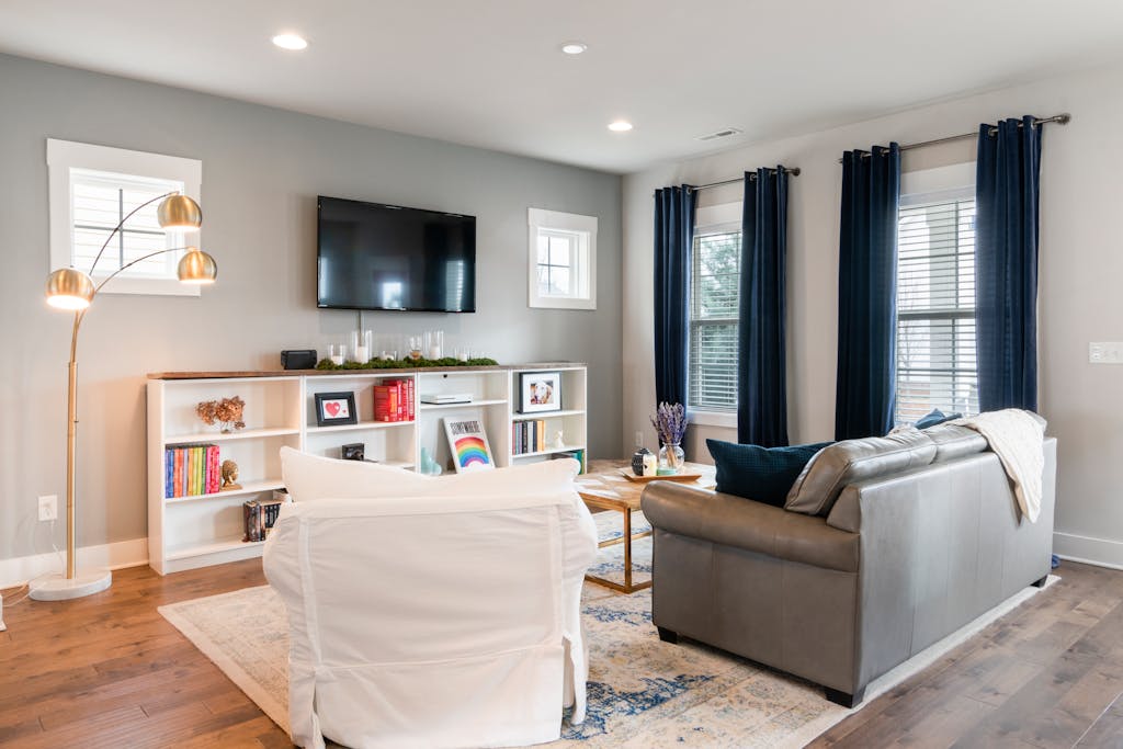 Bright and cozy living room featuring modern minimalist design with a sofa, bookshelf, and stylish lamp.