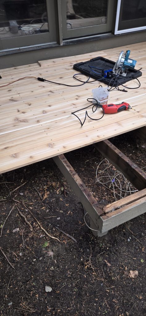 A circular saw and power tools sitting on newly installed natural cedar deck boards during a backyard deck remodel in Dover, New Hampshire.
