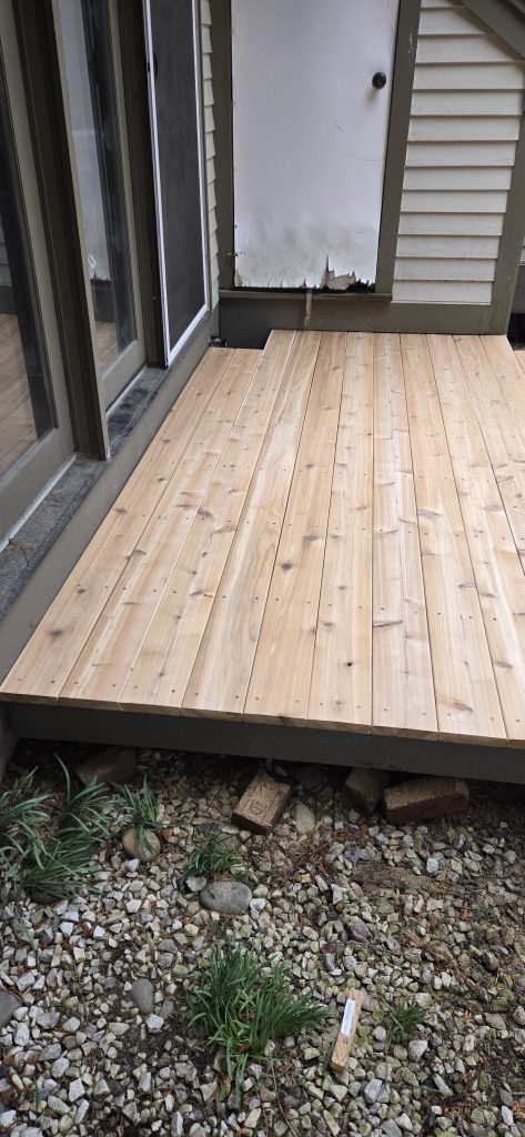 Close up of securely fastened, premium cedar deck boards meeting the threshold of a sliding glass door on a freshly restored deck.