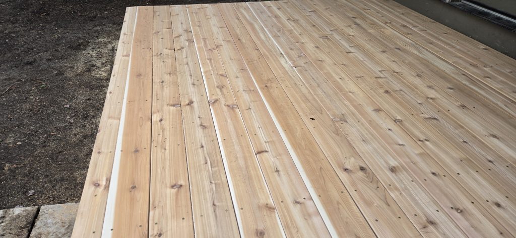 Wide view of a beautiful, newly resurfaced outdoor deck featuring natural cedar wood planks built by a local New Hampshire handyman.
