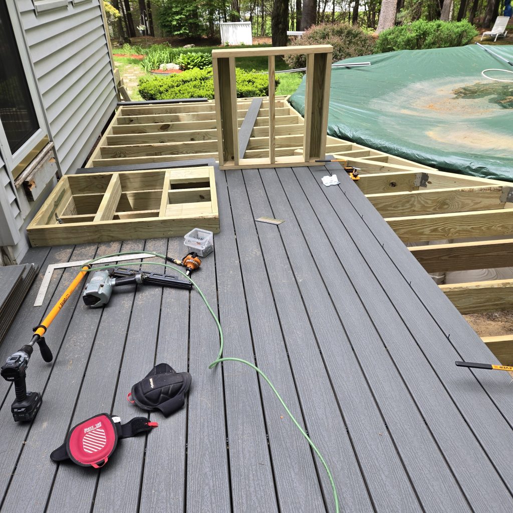 Gray composite deck boards being laid and secured during a custom deck building project