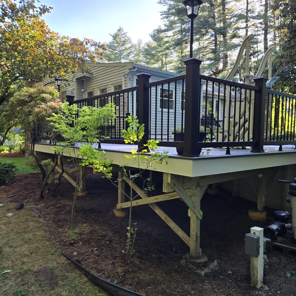 Exposed structural wood framing and heavy cross-bracing underneath a newly built composite pool deck