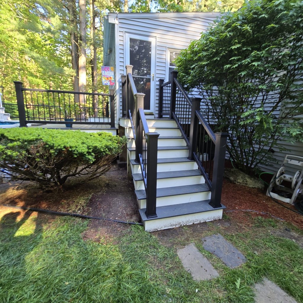 Gray composite backyard steps with safety railings leading up to a residential back entry door