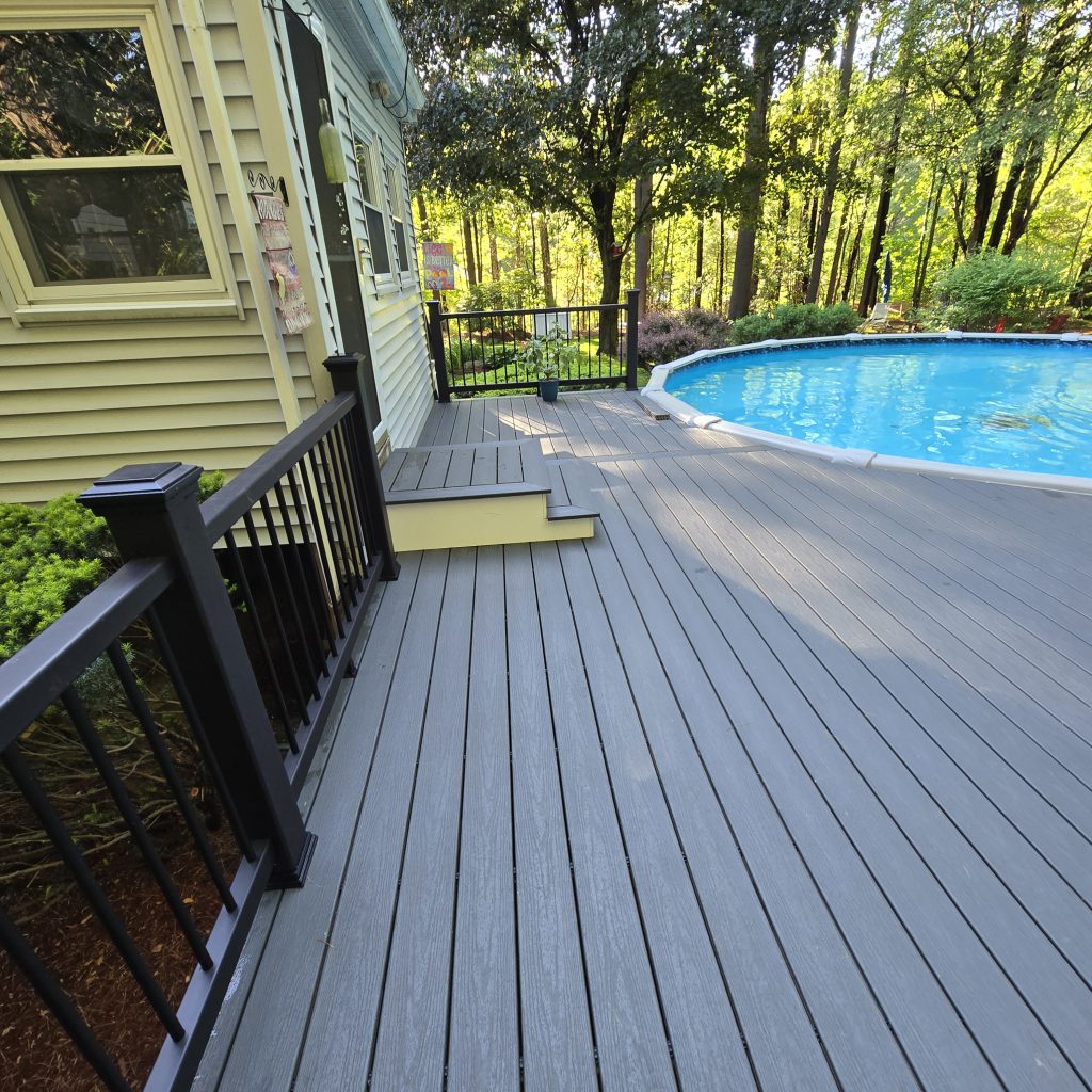 Custom gray composite pool deck with black metal safety railings attached to a residential home