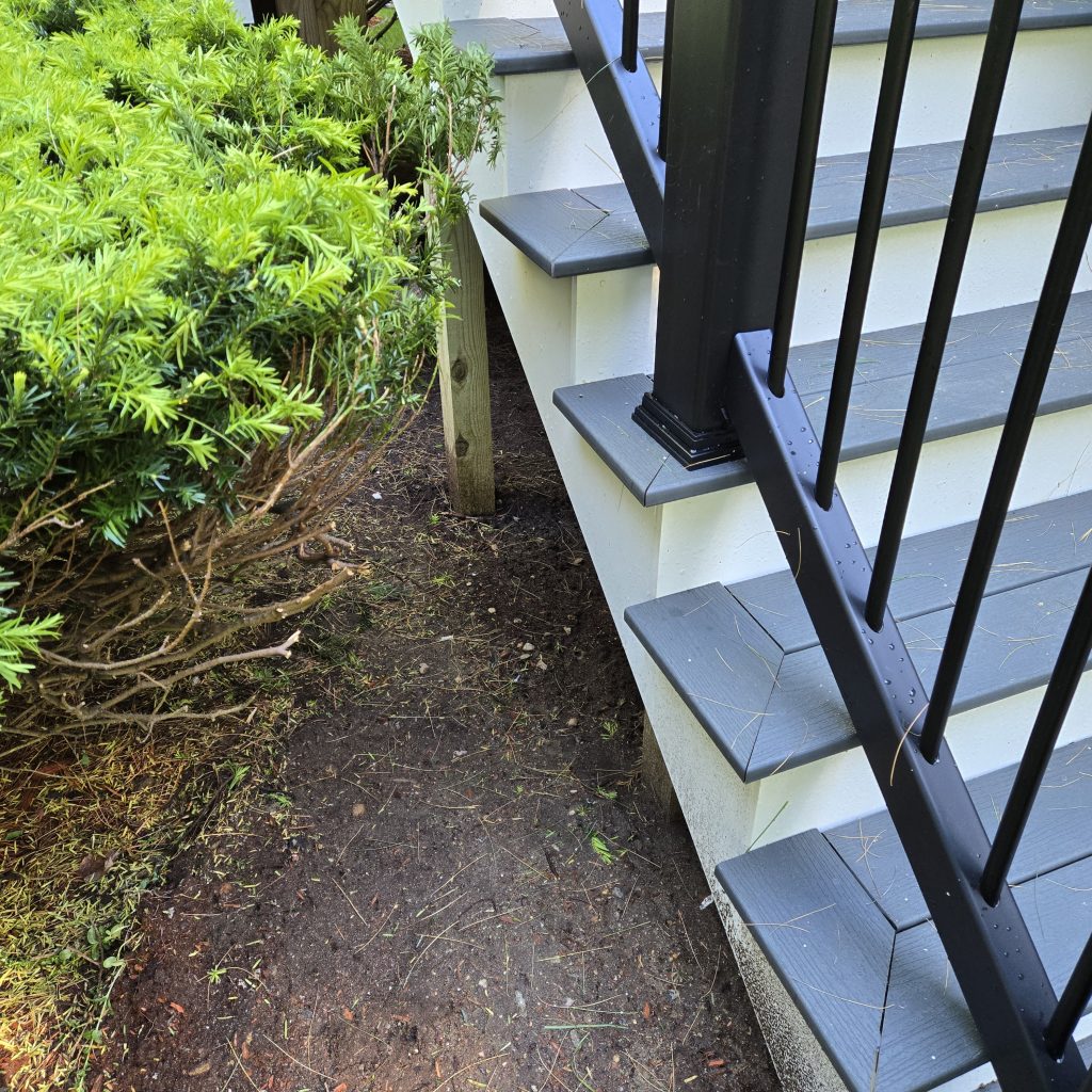lose-up view of newly installed gray composite deck stair treads with white risers and modern black metal safety balusters