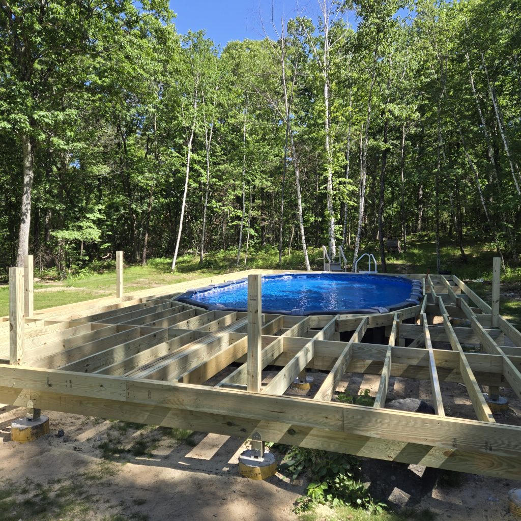 Sturdy pressure-treated wood joists and framing installed securely around an above-ground pool during a custom deck building project
