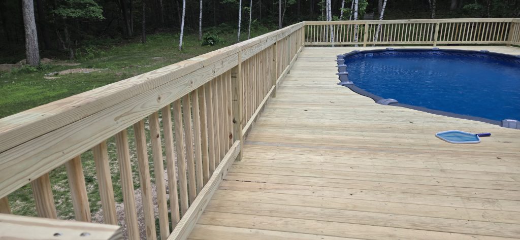View along the secure wooden safety railings and fresh pressure-treated deck boards of a custom above-ground pool deck