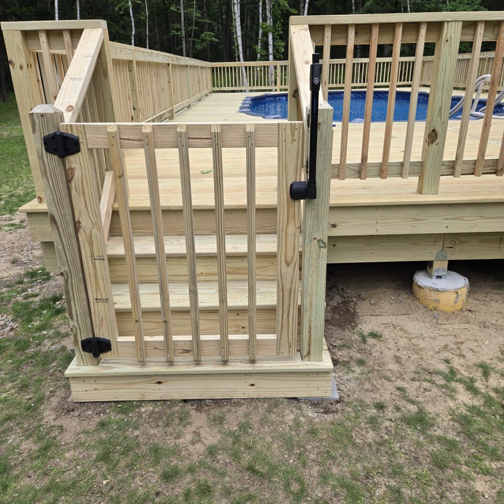 Wooden safety gate and stairs leading up to a new pressure-treated pool deck