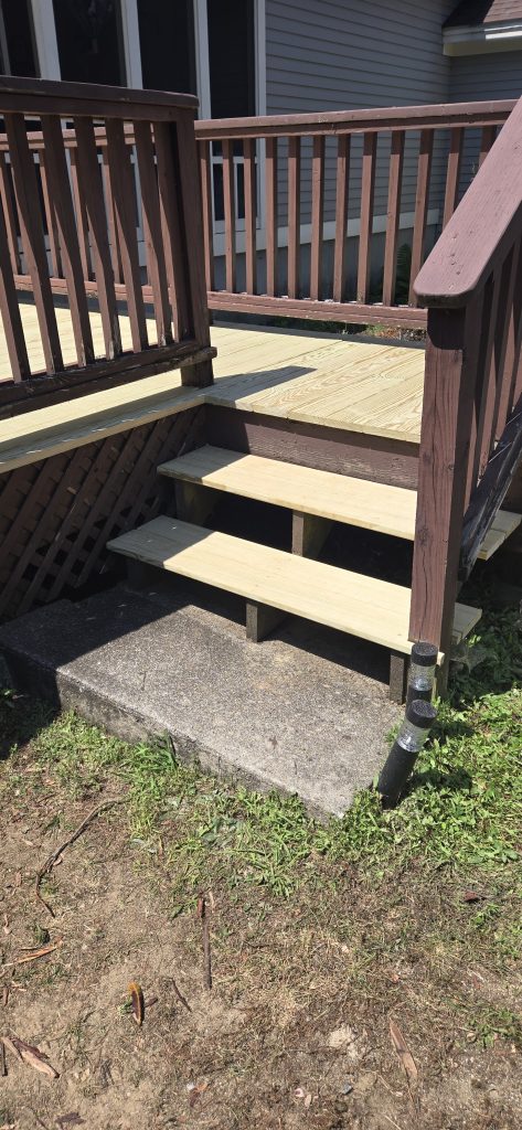 A residential deck in Bow, New Hampshire, featuring newly installed pressure-treated wood floorboards and stair treads integrated with existing brown railings during a deck repair project.