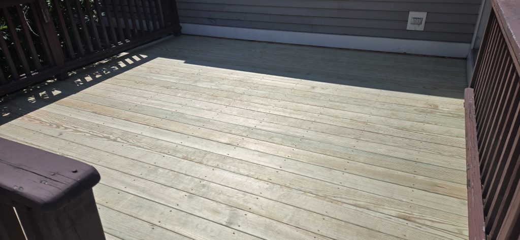 Resurfaced wooden backyard deck with new floorboards and existing brown railings built by Chippy's